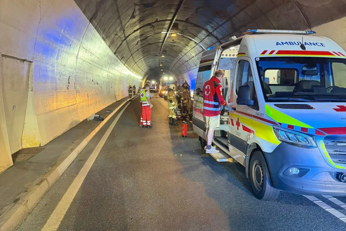 Ein Rettungswagen steht in einem Tunnel, wo Sanitäter und Feuerwehrleute Verletzte versorgen. Die Szene ist beleuchtet und es sind mehrere Einsatzkräfte zu sehen.
