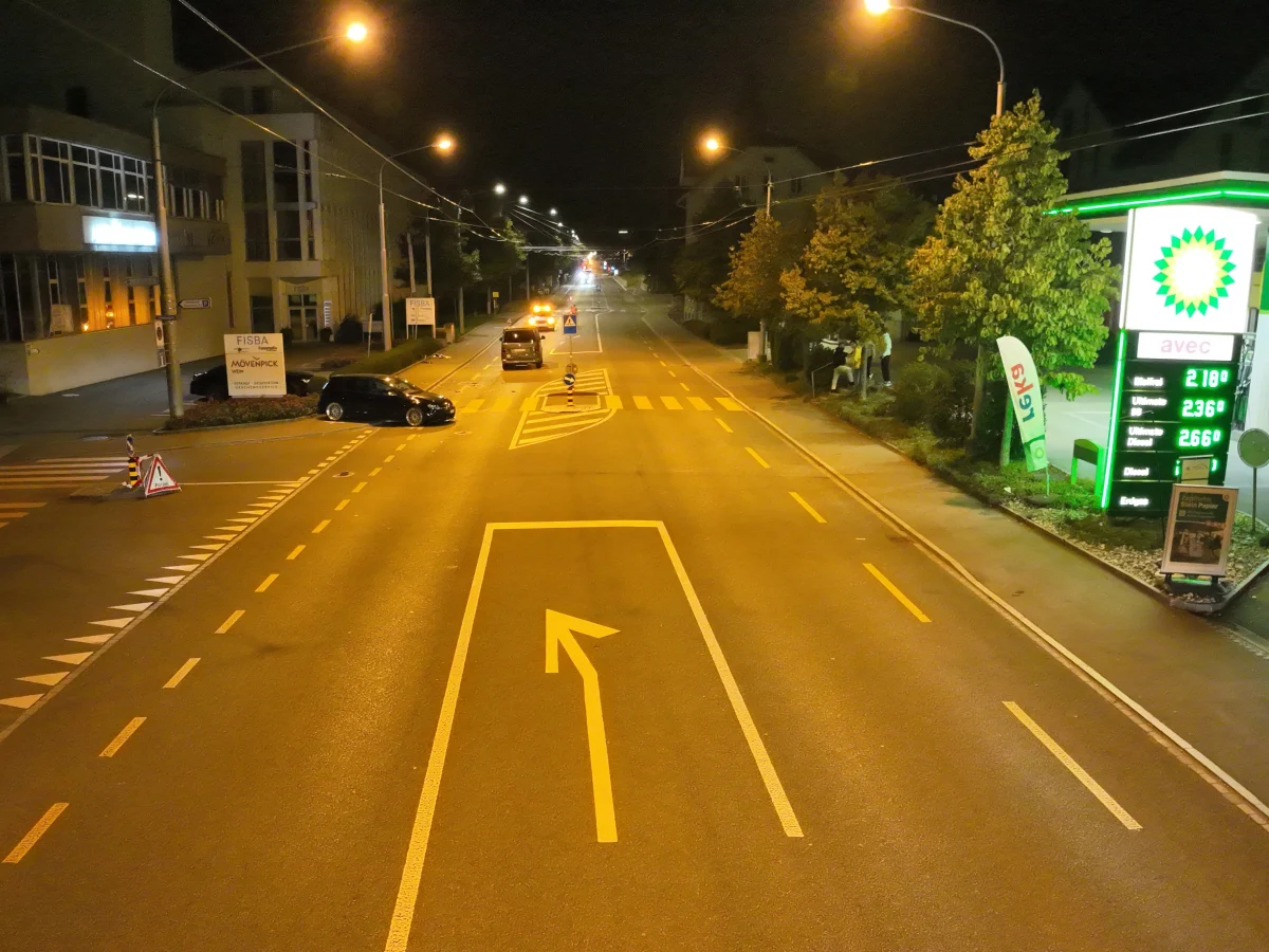 Eine leere Straßenkreuzung bei Nacht mit einem beleuchteten BP-Tankstellenschild auf der rechten Seite. Die Straße ist gut beleuchtet, jedoch sind keine Fahrzeuge in Bewegung zu sehen.