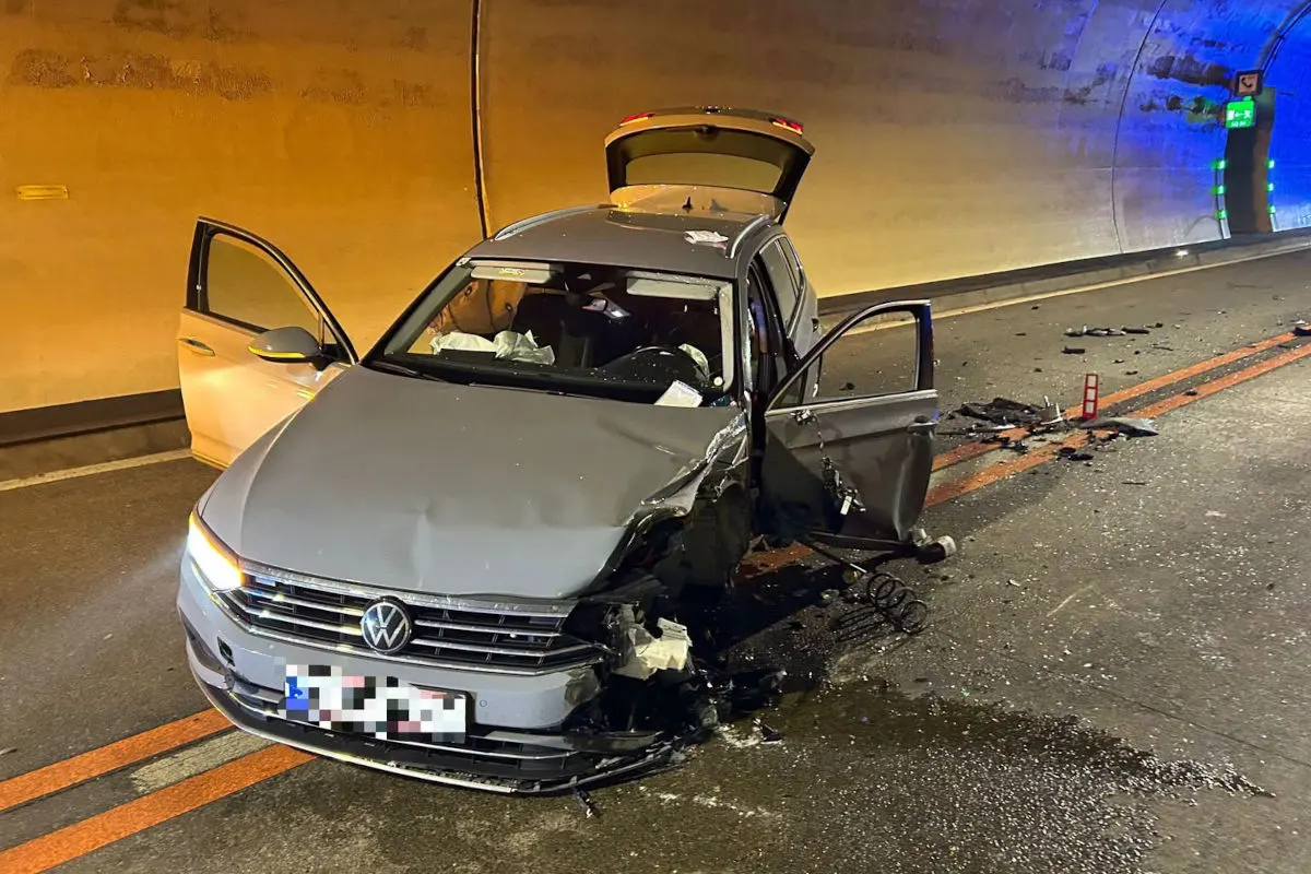 Ein silberner VW mit Frontschaden steht in einem Tunnel. Türen und Kofferraum sind offen, Wrackteile liegen auf der Straße.
