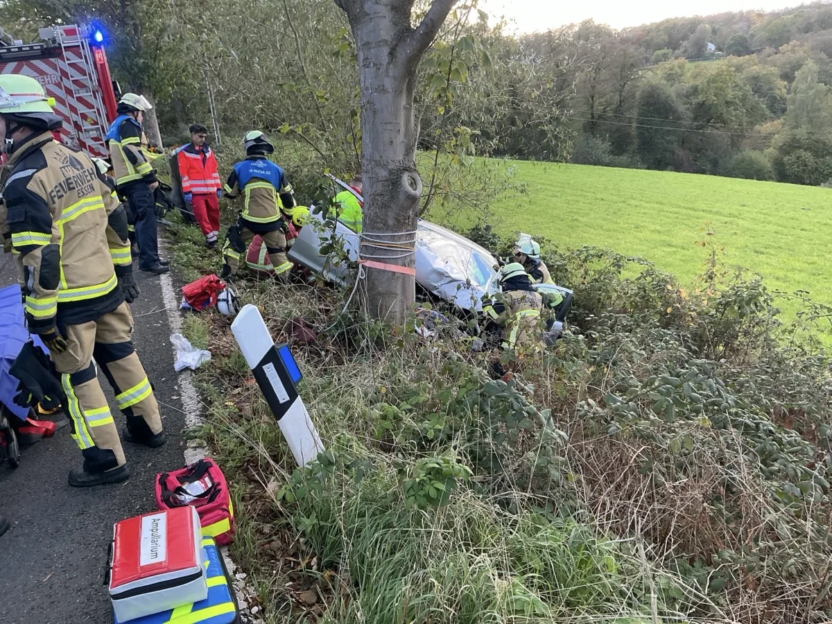 Feuerwehrleute sind dabei, ein Auto zu bergen, das neben einer Landstraße in einem Graben gelandet ist. Mehrere Einsatzkräfte sind um das Fahrzeug herum tätig.