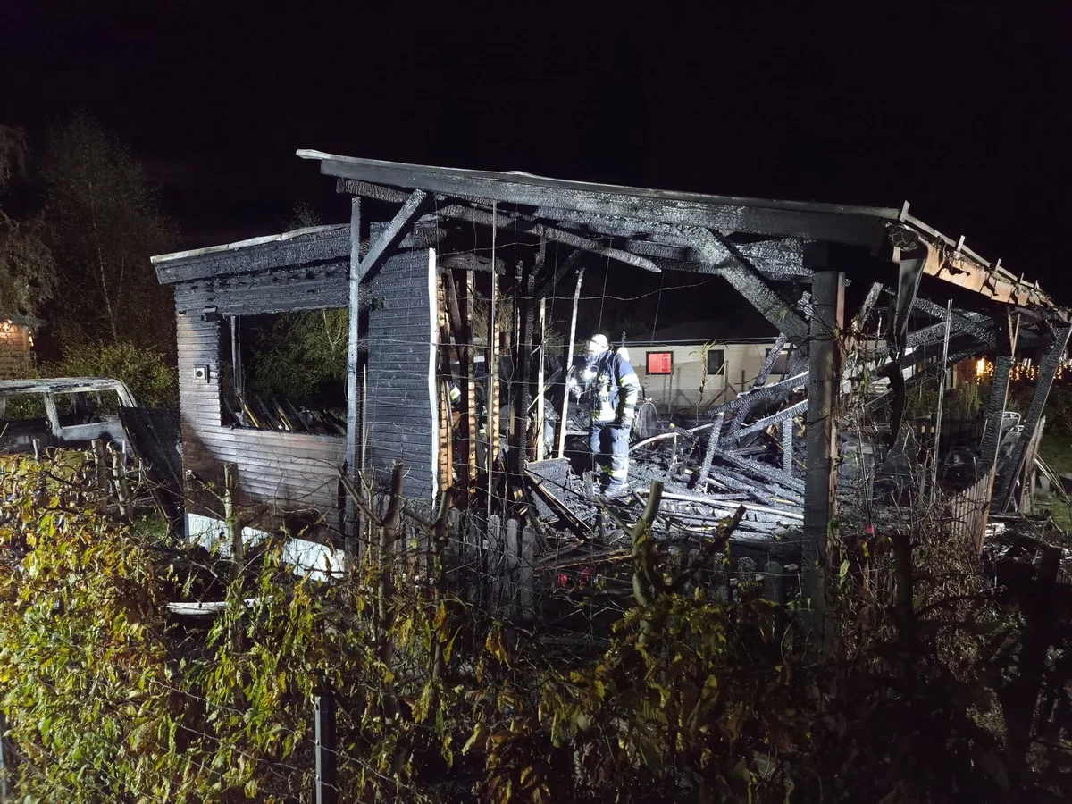 Ein Feuerwehrmann steht inmitten der abgebrannten Ruine eines Hauses, das vom Brand stark beschädigt wurde.