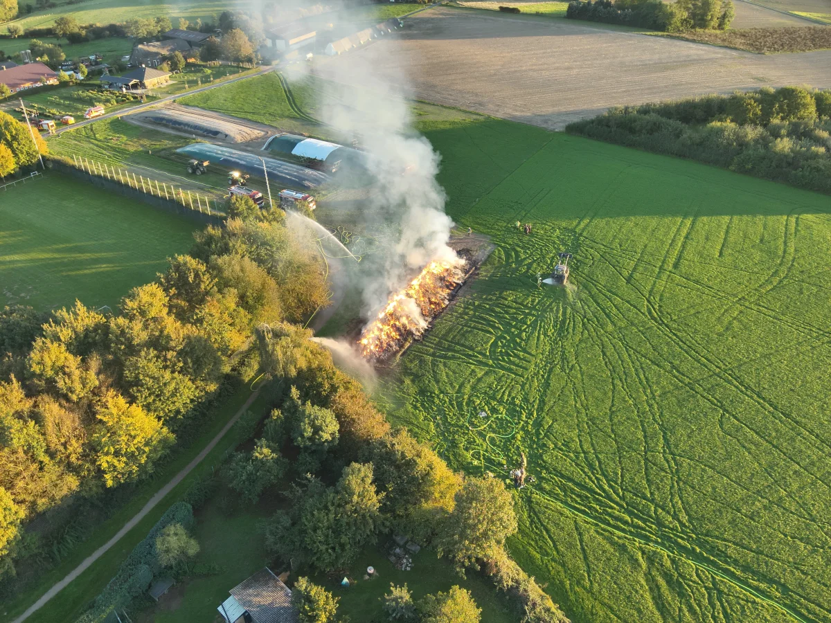 Von oben sieht man ein brennendes Feld, das von Feuerwehrfahrzeugen aus verschiedenen Richtungen gelöscht wird.
