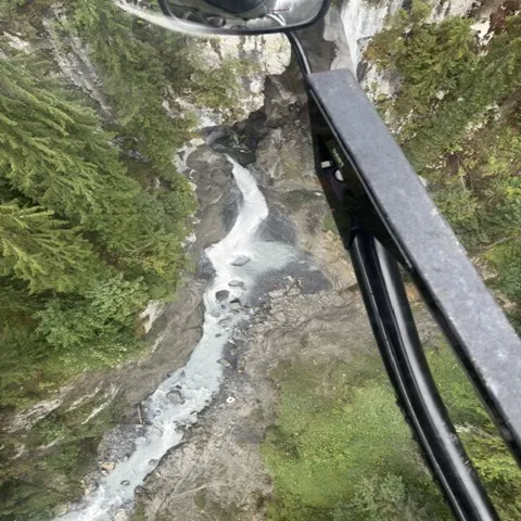 Das Bild zeigt eine felsige Schlucht mit einem Fluss, aufgenommen aus der Luft in einem bewaldeten Gebiet.