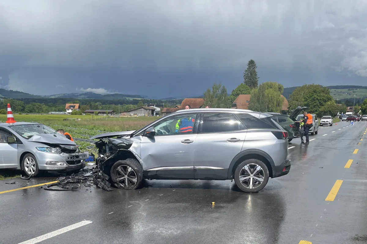 Ein silbernes Auto mit Frontschaden steht seitlich auf der Straße. Ein weiteres Auto mit ähnlichem Schaden steht daneben. Personen in Warnwesten sind vor Ort.