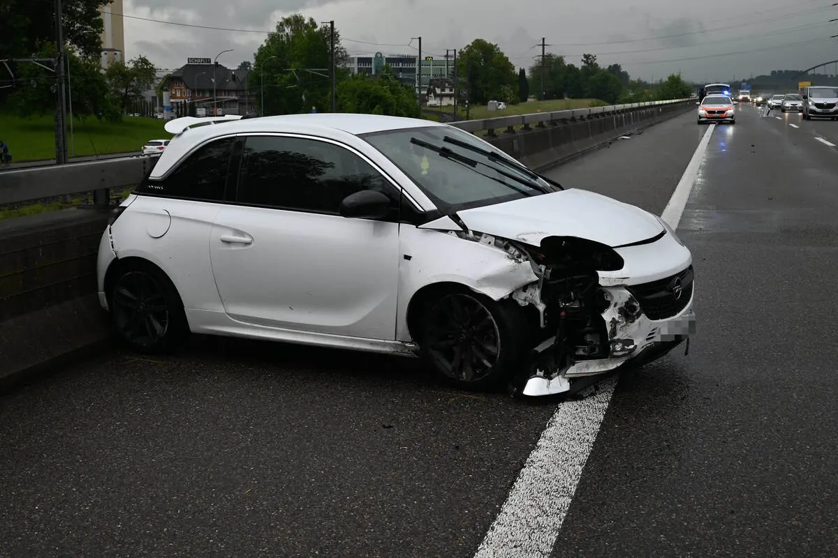 Ein weißer Opel mit schwer beschädigter Front steht auf der Standspur einer Autobahn. Im Hintergrund nähert sich ein Polizeifahrzeug.