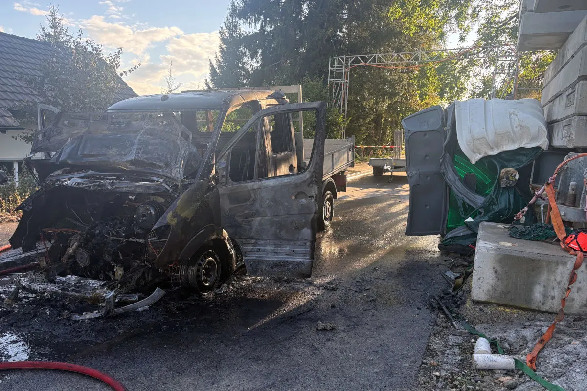 Ein Transporter ist komplett ausgebrannt und steht auf einer Straße. Es ist Tag und das Fahrzeug zeigt deutliche Brandschäden.