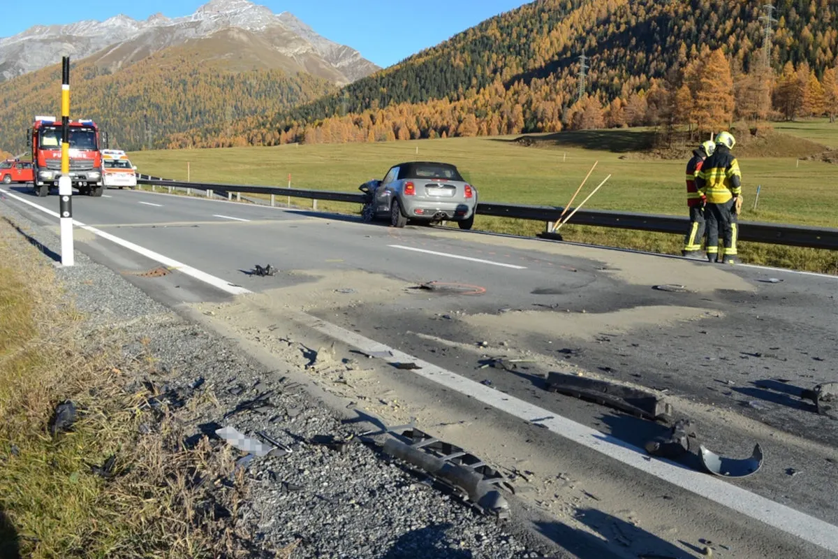 Ein graues Auto steht nach einem Unfall mit der Leitplanke auf einer Landstraße. Die Feuerwehr ist vor Ort bei herbstlichem Wetter.