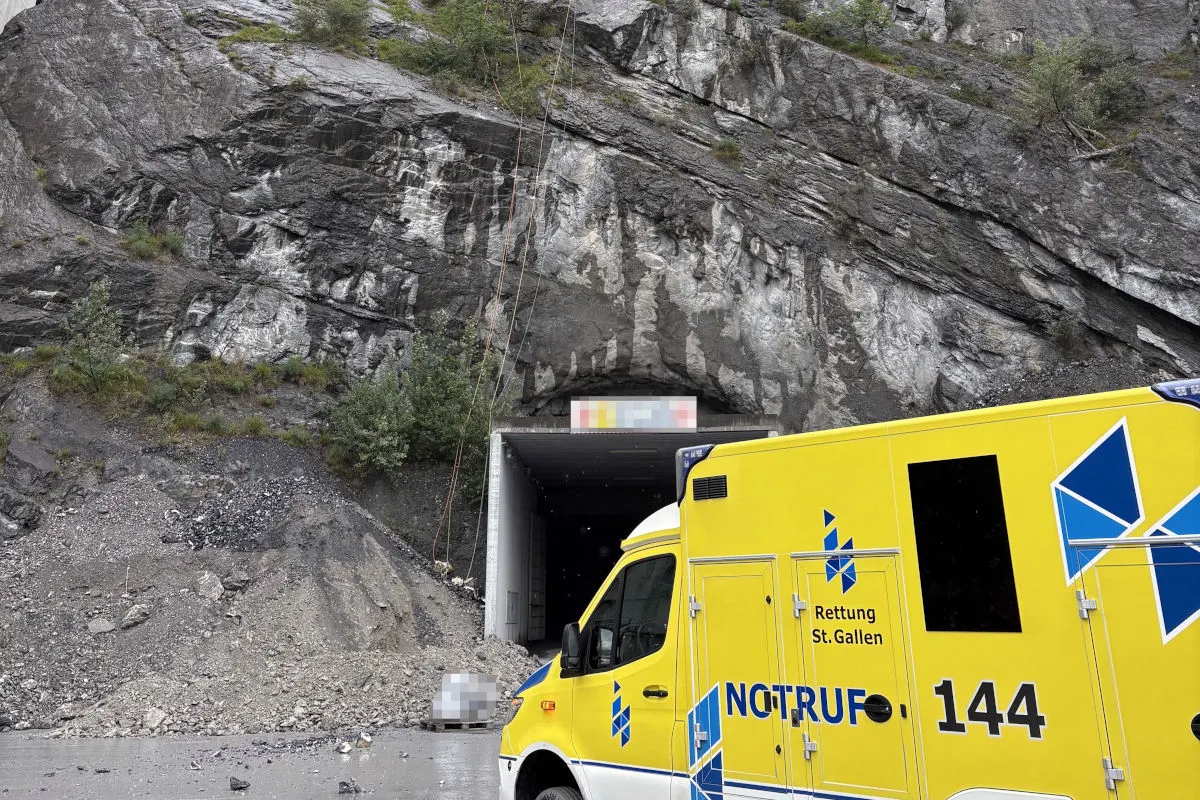 Ein gelbes Rettungsfahrzeug der Rettung St. Gallen steht vor einem Tunnel vor einem felsigen Berghang, wo Geröll zu sehen ist.