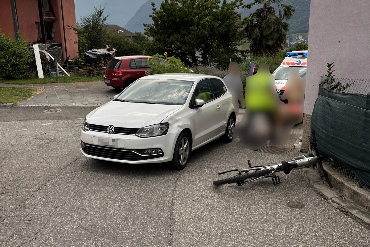 Auf einer Straße steht ein weißer VW, daneben liegt ein umgestürztes Fahrrad. Im Hintergrund ist ein Polizeieinsatzwagen sichtbar.