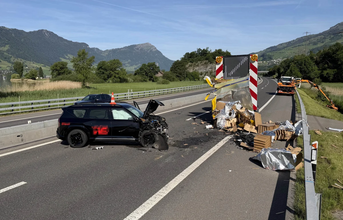 Ein schwer beschädigtes schwarzes Fahrzeug steht auf einer Autobahn. Trümmer und Bauabsperrungen sind ebenfalls sichtbar.