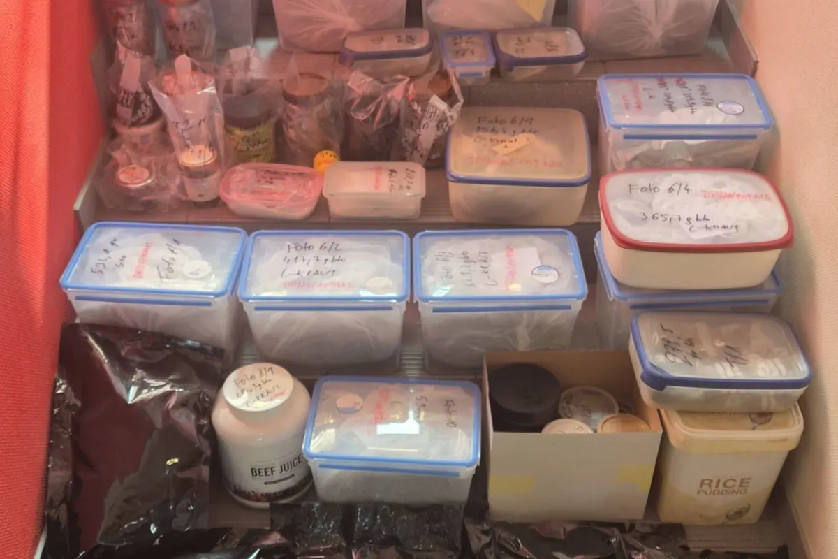 Verschiedene beschriftete Behälter stehen auf einem Regal, einige in Plastik eingewickelt, andere in Kartons.