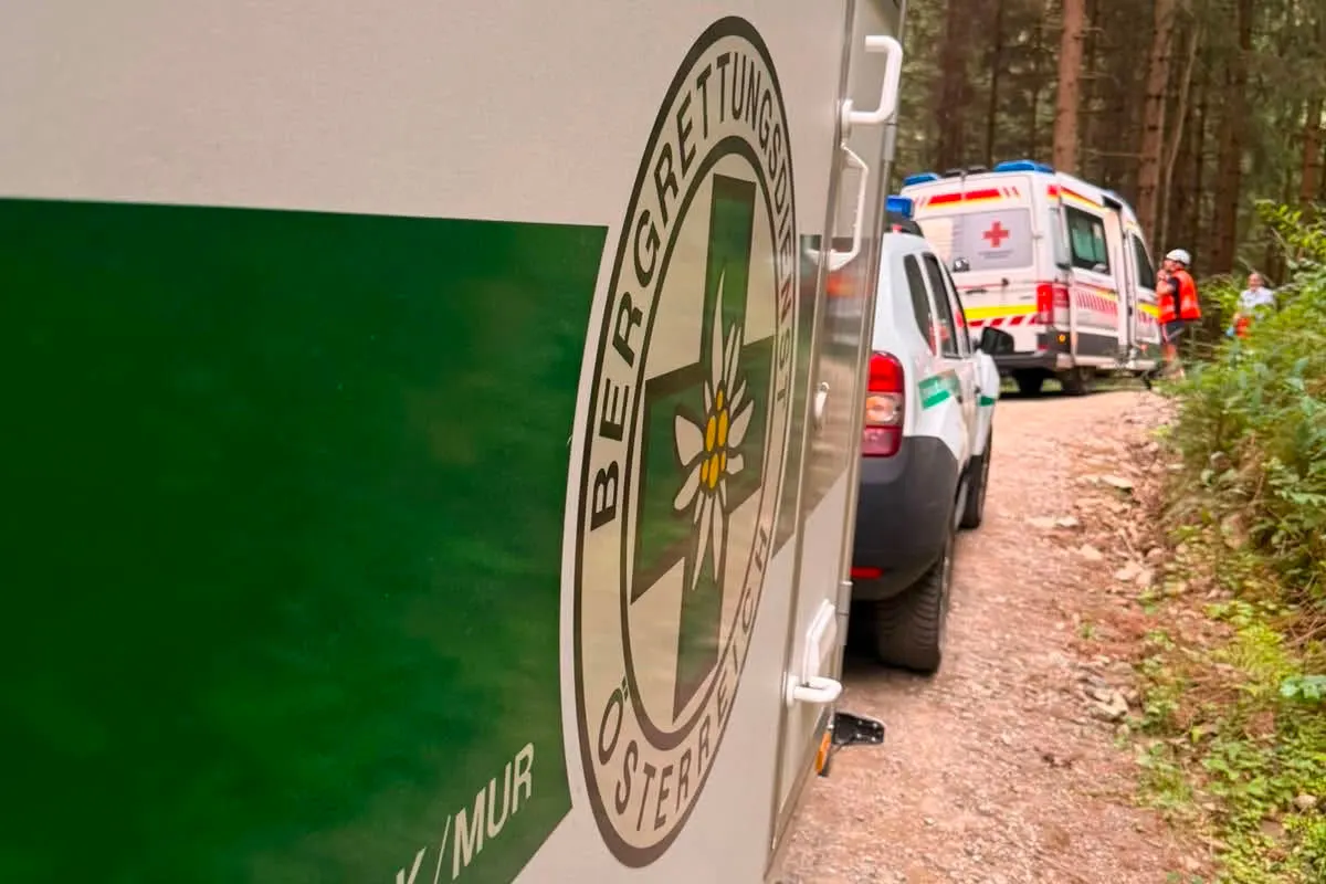 Ein Fahrzeug des Bergrettungsdienstes Österreich parkt auf einem Waldweg neben einem Rettungswagen. Rettungskräfte sind zu erkennen.