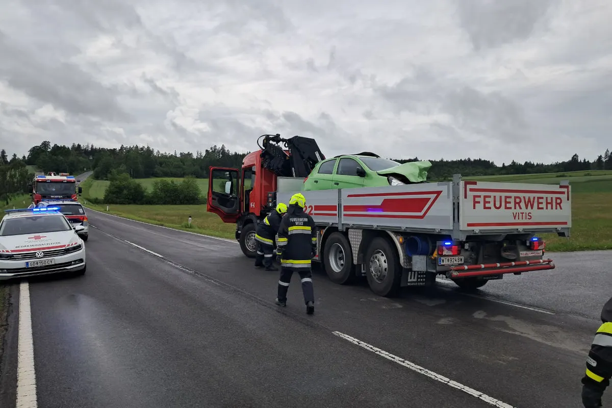 Ein grünes Auto wird von einem Lkw der Feuerwehr Vitis auf einer Landstraße transportiert. Der Himmel ist bewölkt.