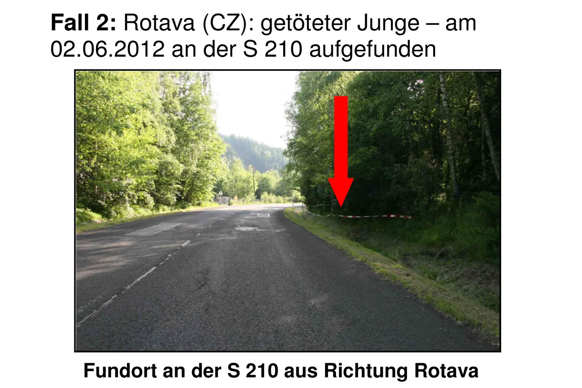 Eine asphaltierte Straße in ländlicher Umgebung, daneben Bäume und ein Absperrband am Straßenrand.