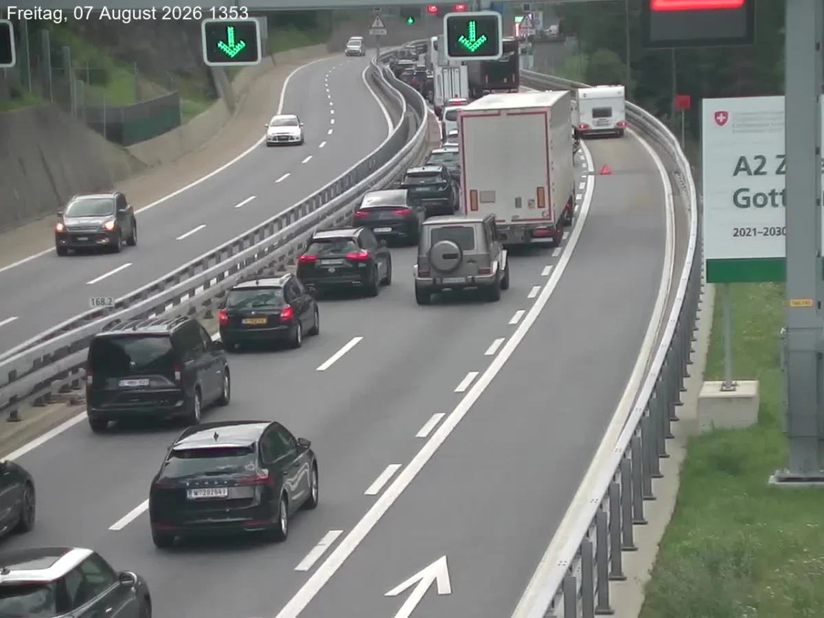 Mehrere Fahrzeuge stauen sich auf der A2 vor dem Gotthardtunnel. Verkehrsschilder zeigen grüne Pfeile.