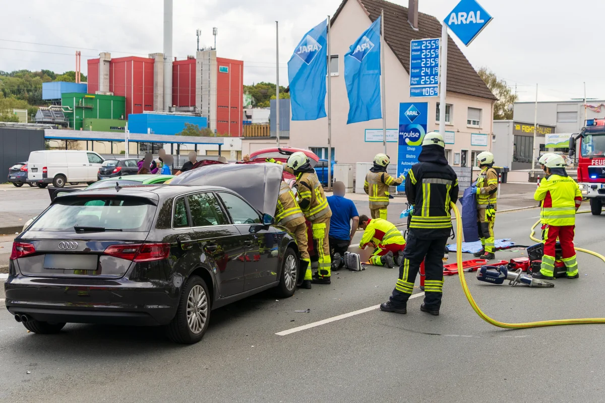 Vor einer Tankstelle leisten mehrere Rettungskräfte Erste Hilfe bei einer verletzten Person, umgeben von Einsatzfahrzeugen.