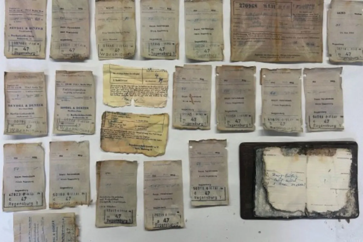 Eine Sammlung von verblassten und abgenutzten Dokumenten liegt auf einer weißen Oberfläche ausgebreitet. Die Dokumente scheinen historisch wertvoll zu sein.