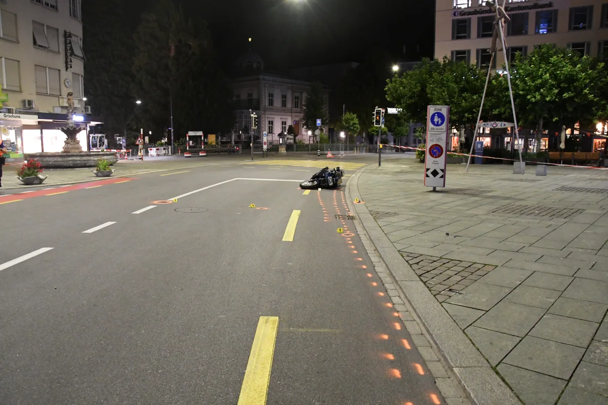Ein Motorrad liegt umgekippt auf einer leeren Straßenkreuzung in der Nacht. Es sind Absperrungen und Markierungen auf der Fahrbahn sichtbar.