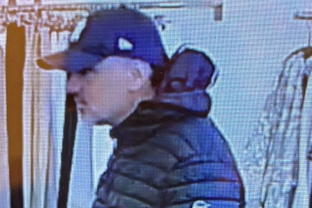 Ein Mann mit schwarzer Mütze und Jacke steht in einem hellen Raum, er blickt zur Seite.