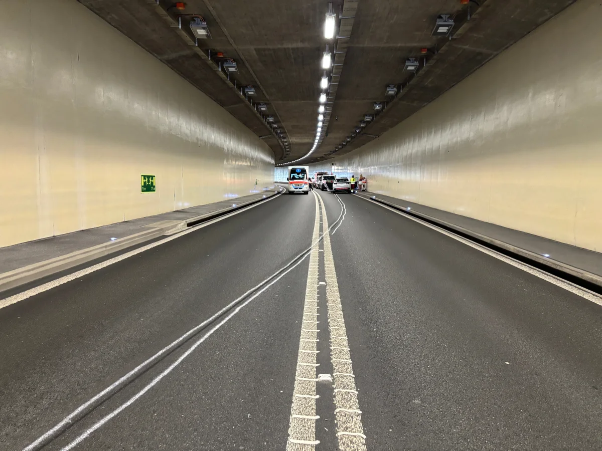 Ein Tunnel ist durch mehrere Einsatzfahrzeuge und Personen in leuchtenden Westen teilweise blockiert.