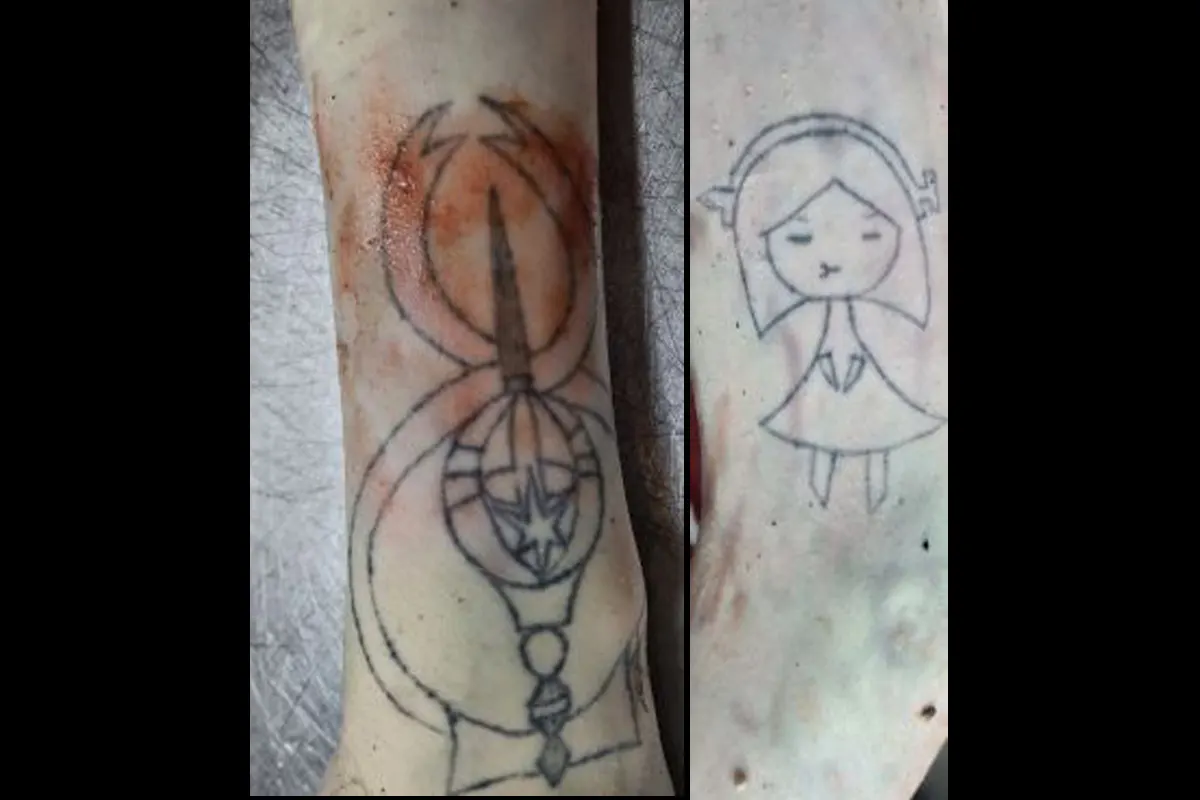 Der Unterarm zeigt zwei Tattoos: ein abstraktes Design mit Kreisen und ein stilisiertes Mädchen mit geschlossenen Augen.