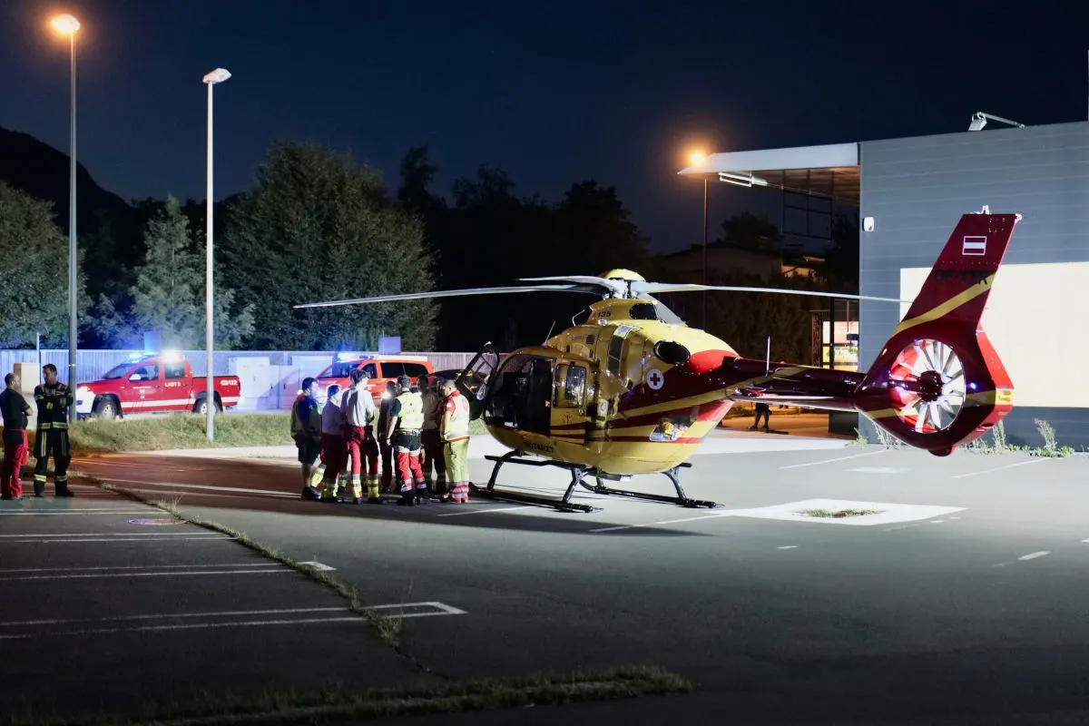 Ein Rettungshubschrauber steht auf einem Parkplatz bei Nacht. Mehrere Einsatzkräfte sind in der Nähe des Hubschraubers versammelt.
