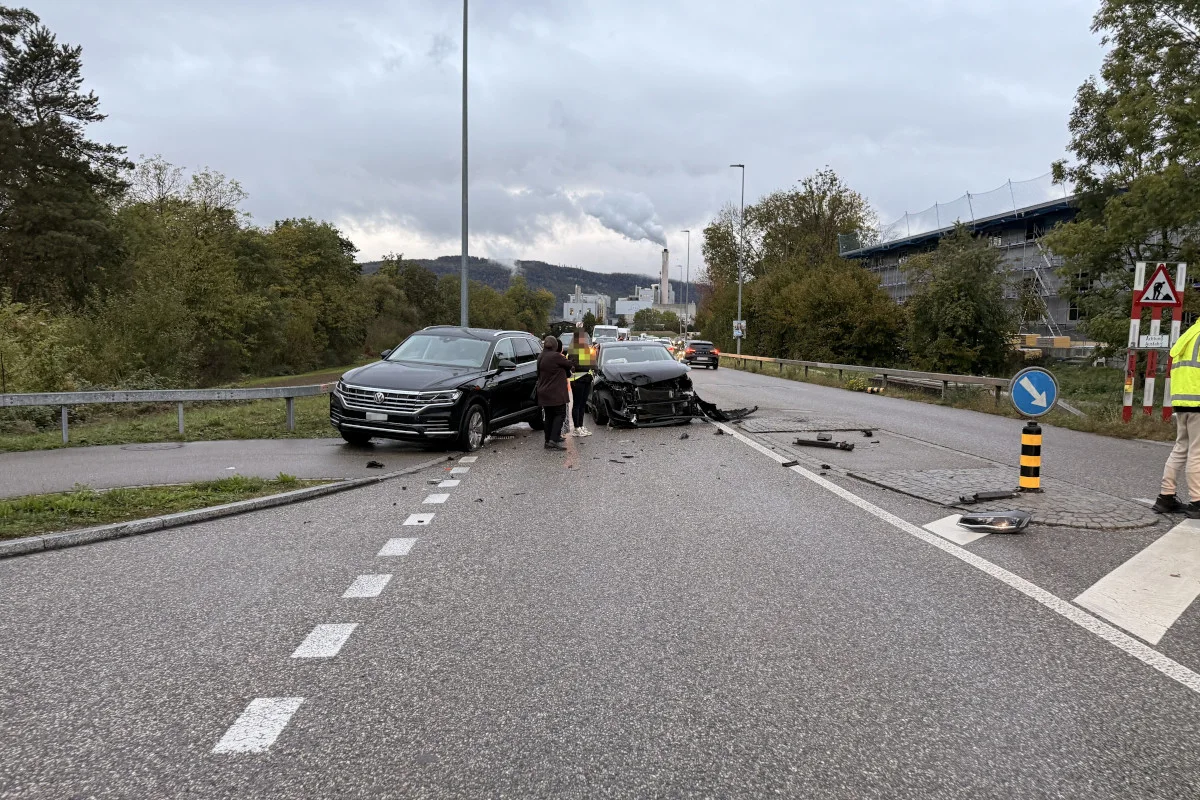 Zwei Autos sind auf einer Straße nach einem Unfall beschädigt zu sehen. Es gibt Trümmer auf der Straße, und ein Mann steht daneben.