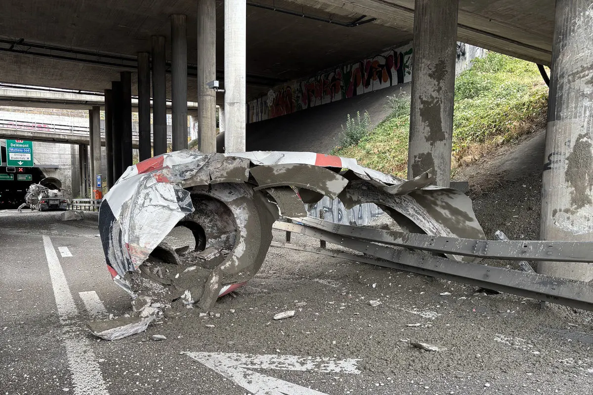 Das Bild zeigt eine stark beschädigte Überkopf-Signalisation unter einer Autobahnbrücke. Trümmer und Betonstücke sind auf der Straße verteilt.