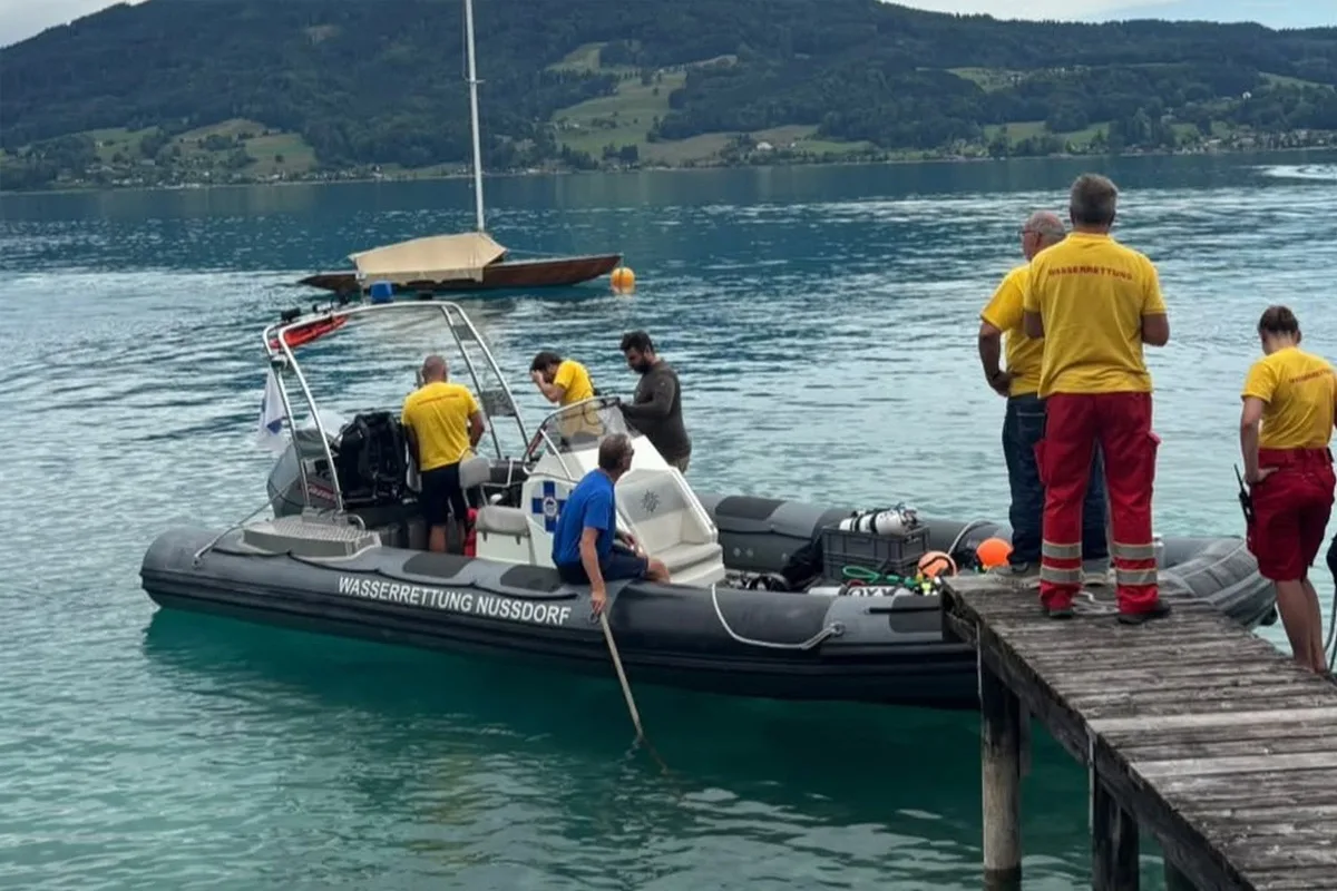 Ein Rettungsboot der Wasserrettung Nussdorf liegt am Steg. Mehrere Personen in gelber Schutzkleidung sind auf dem Boot und am Ufer zu sehen.