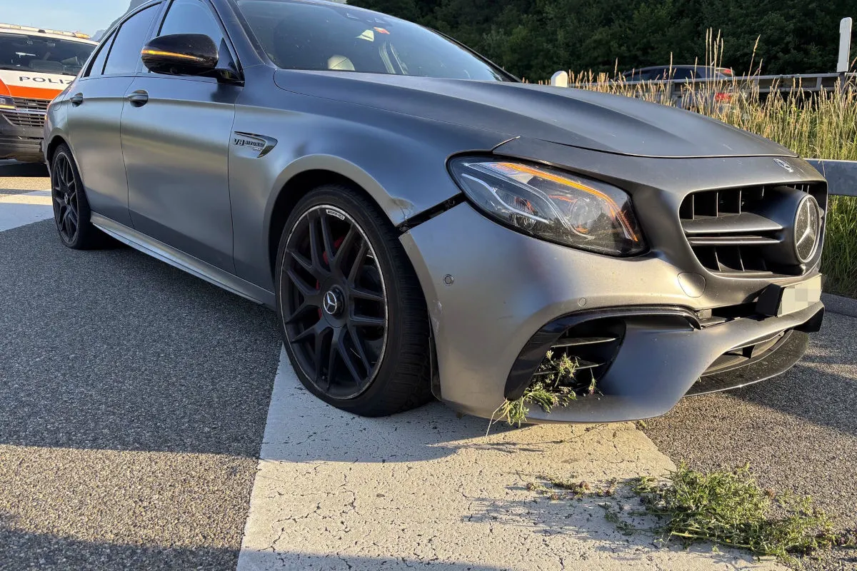 Ein silbergrauer Mercedes zeigt Schäden an der Frontpartie, mit Pflanzen im Stoßfänger auf einer Straße.