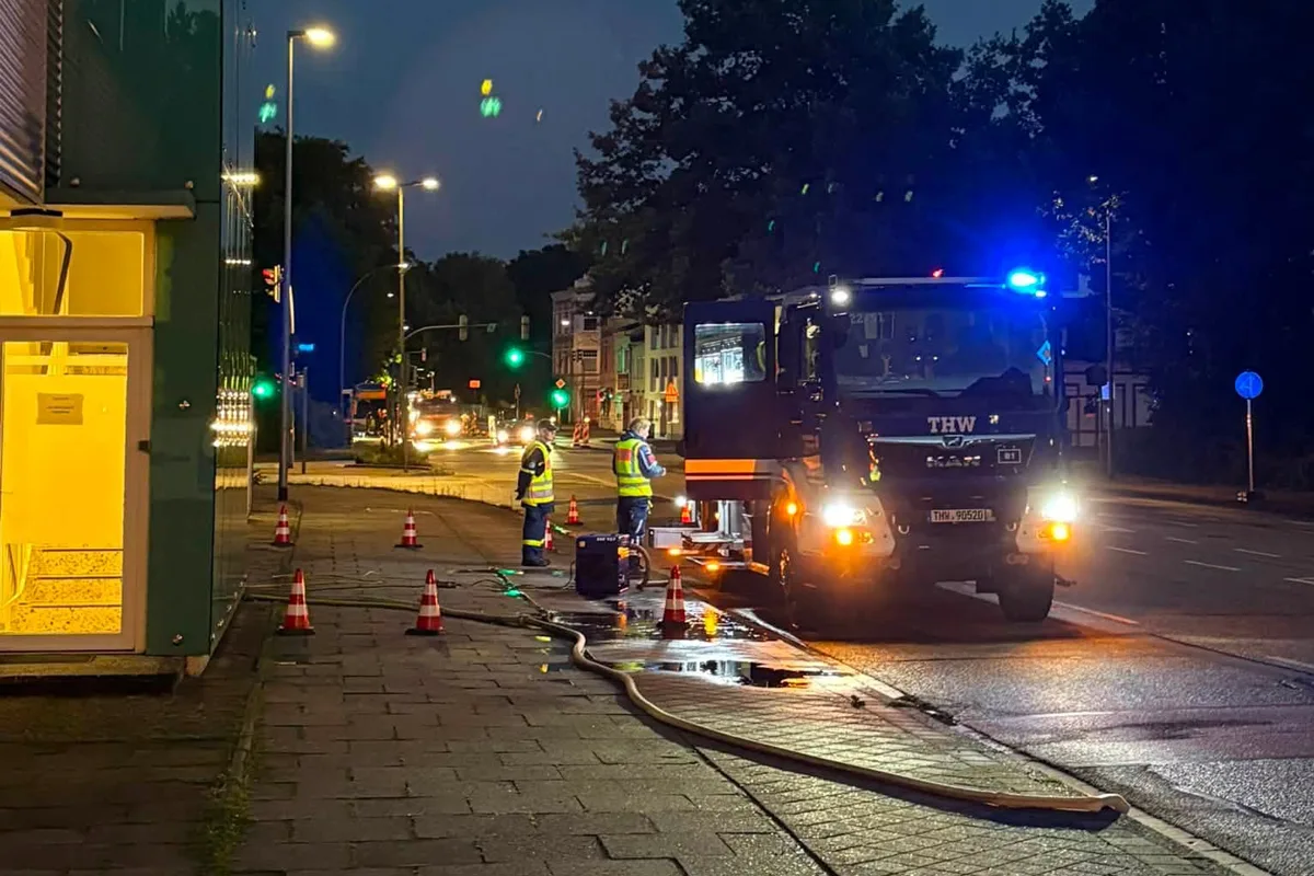 Ein Fahrzeug des Technischen Hilfswerks mit blinkendem Blaulicht steht auf einer beleuchteten städtischen Straße bei Nacht.