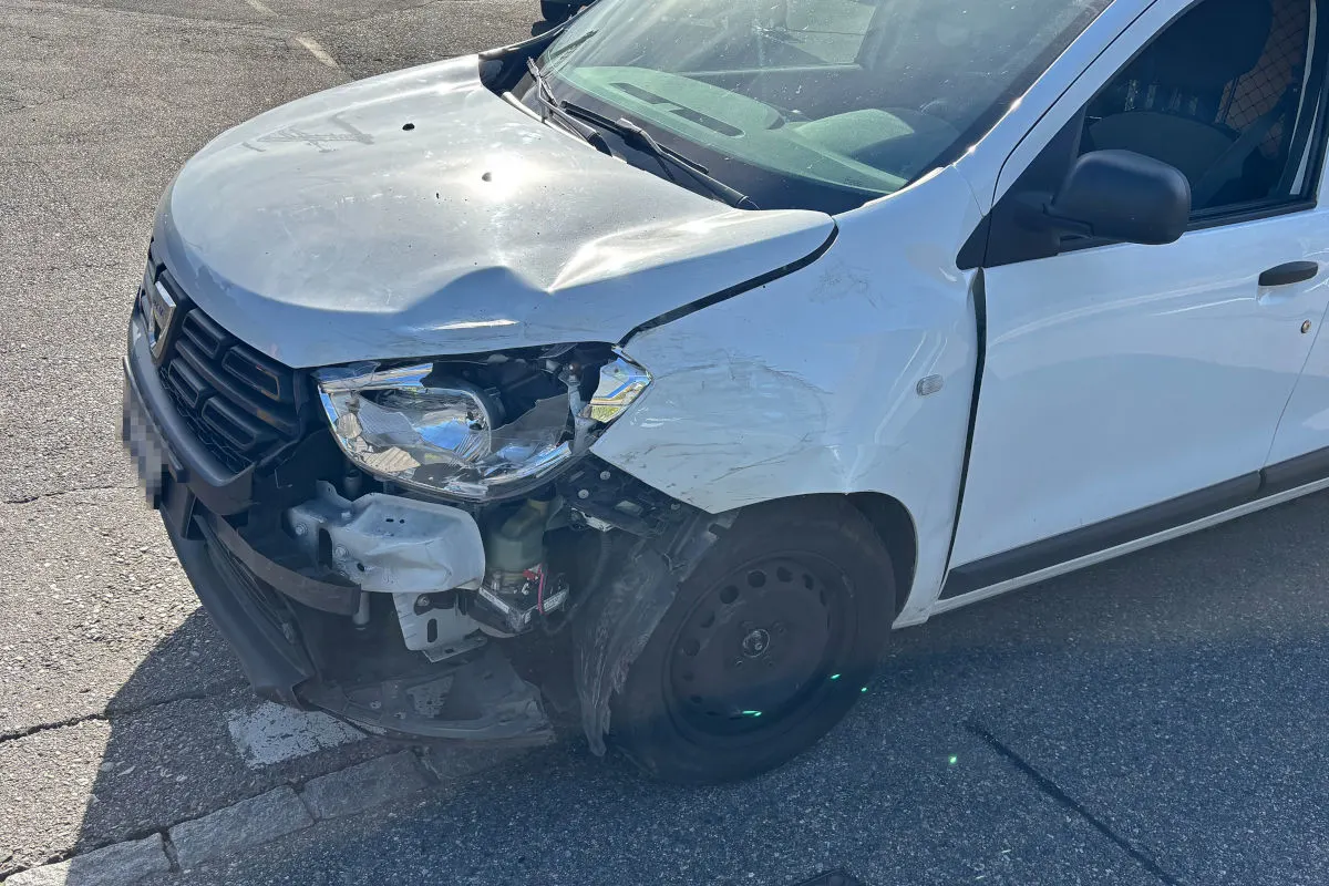 Ein weißes Auto zeigt deutliche Frontschäden nach einem Verkehrsunfall. Der rechte Scheinwerfer ist zerbrochen und die Stoßstange eingedrückt.