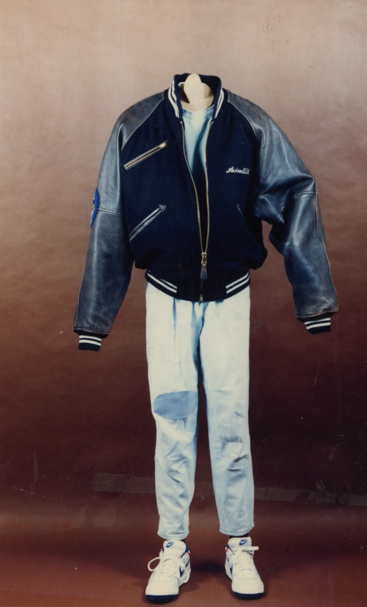 Eine Jeansjacke und Hose auf einer Schaufensterpuppe ohne Kopf, mit weißen Sneakers.