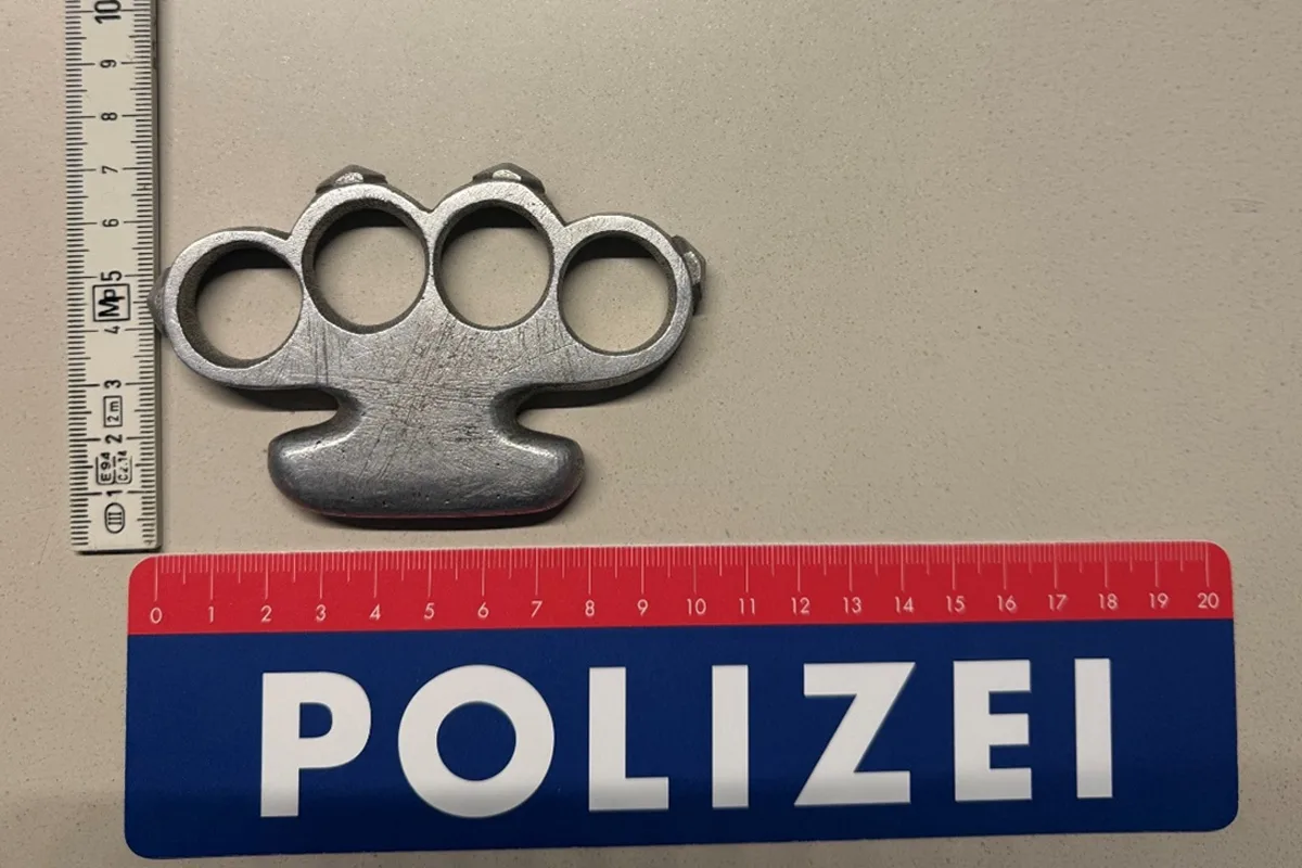 Ein metallener Schlagring liegt auf einem Tisch, flankiert von einem Maßband und einem Polizei-Lineal.