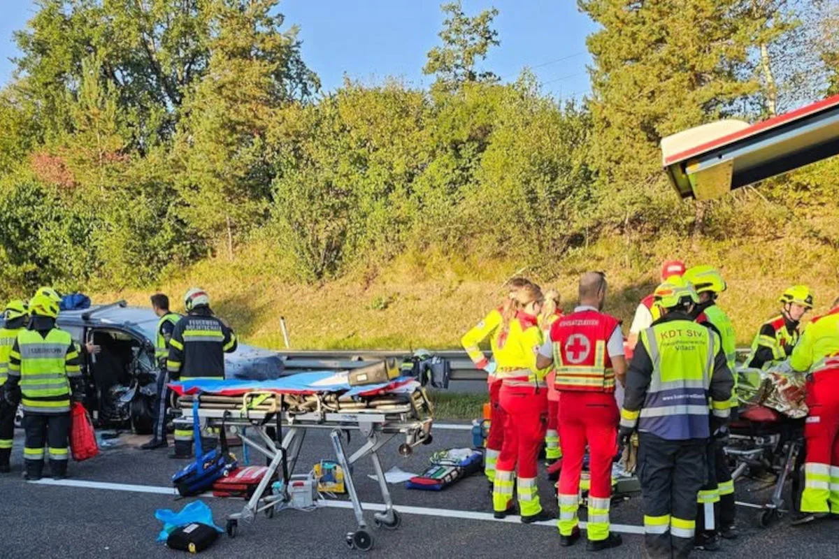Mehrere Rettungskräfte stehen um ein verunfalltes Fahrzeug auf einer Autobahn. Ein Tragebett ist sichtbar.