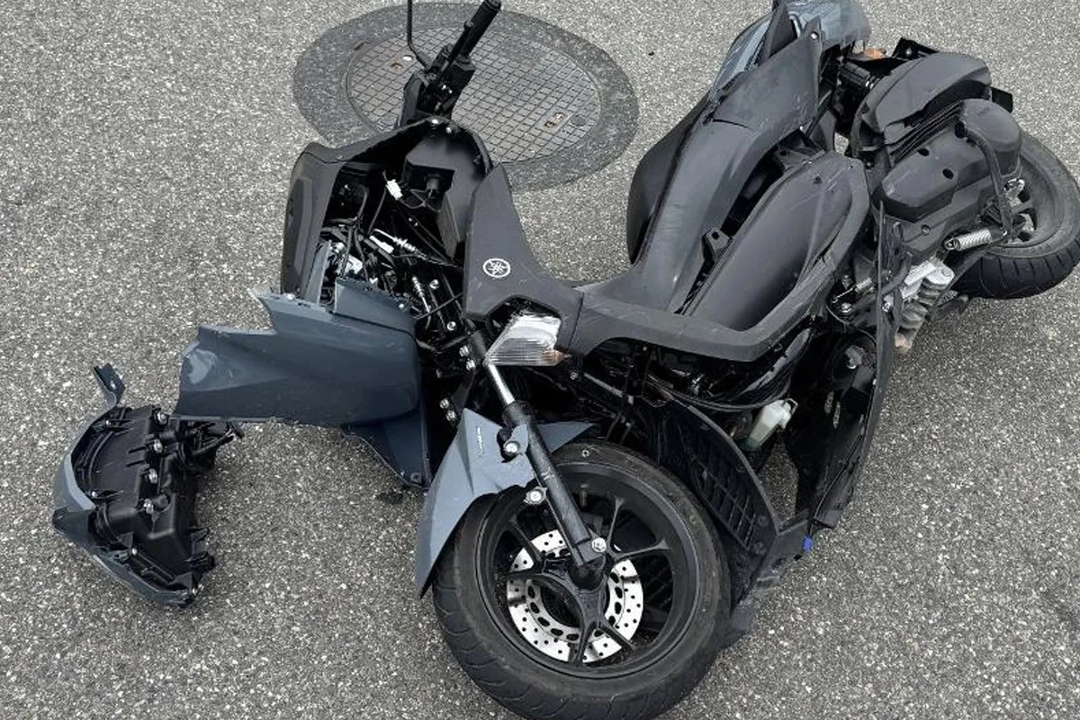 Ein stark beschädigtes Motorrad liegt auf dem grauen Asphalt. Einzelne Teile sind abgebrochen.