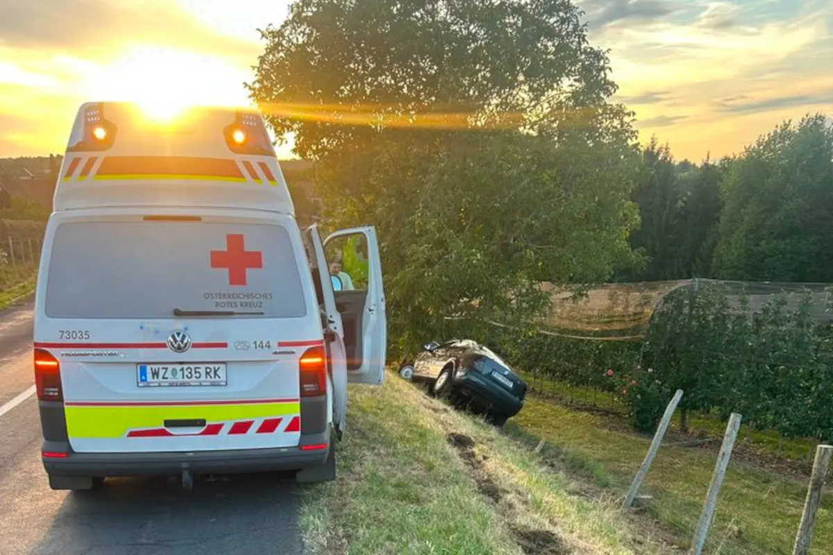 Ein Rettungswagen des Österreichischen Roten Kreuzes steht am Straßenrand, während ein schwarzer Pkw in die Böschung gefahren ist.