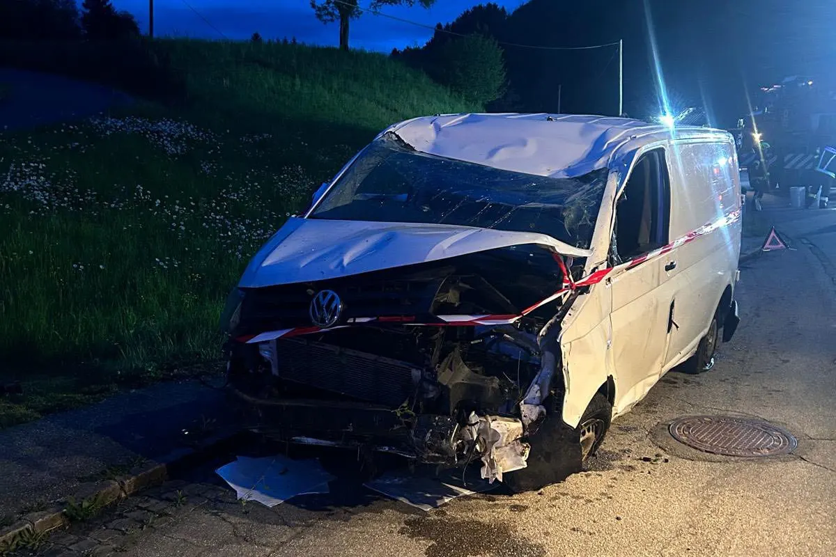Ein weißer VW Transporter mit stark beschädigter Front steht am Rand einer Straße. Die Szene ist bei Nacht aufgenommen, mit deutlicher Dellenbildung an der Karosserie und dem Einsatz von Absperrband sichtbar.
