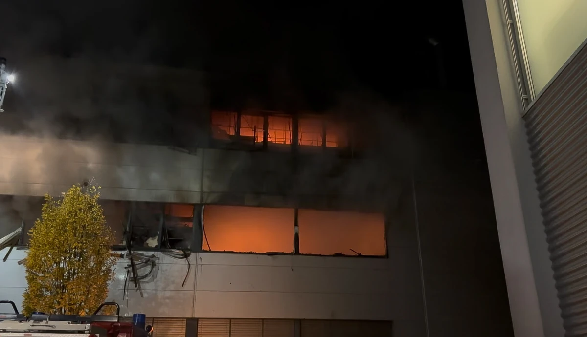 In der Nacht dringen Rauch und orangefarbene Flammen aus mehreren Fenstern eines mehrstöckigen Gebäudes.