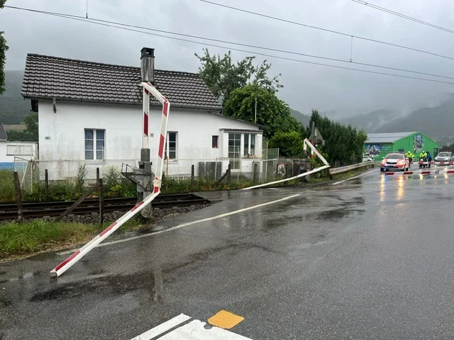 Die Bahnschranke liegt beschädigt und schräg über der Fahrbahn, während im Hintergrund ein Polizeiwagen zu sehen ist.