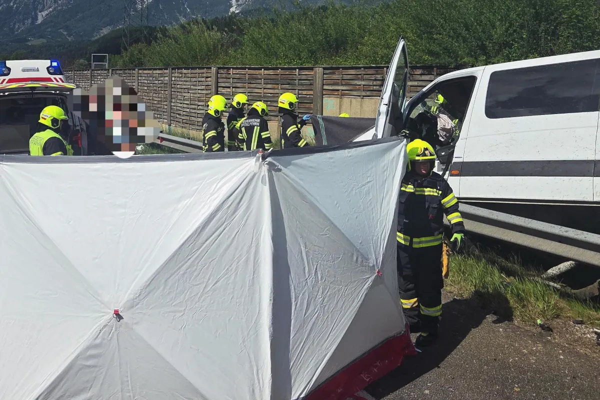 Mehrere Einsatzkräfte in Schutzkleidung stehen um einen weißen Van. Ein weißer Sichtschutz ist im Vordergrund aufgestellt.