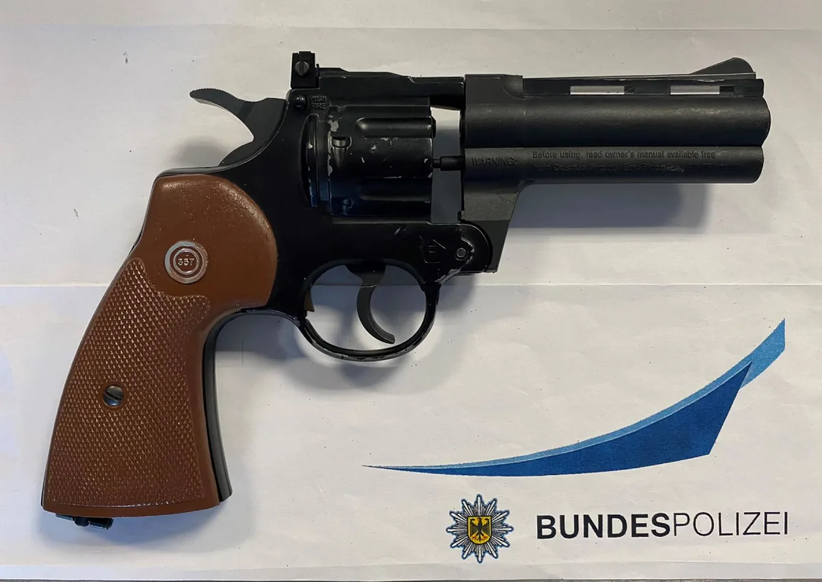 Die Abbildung zeigt eine Pistole mit braunem Griff auf einem Papier, das das Logo der Bundespolizei trägt.