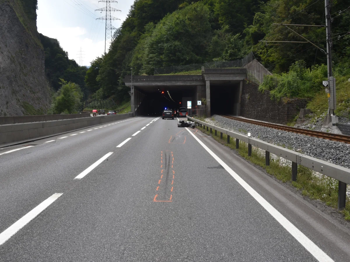 Ein umgekipptes Motorrad liegt auf der Fahrbahn vor einem Tunnel auf der Autobahn. Polizei ist vor Ort.