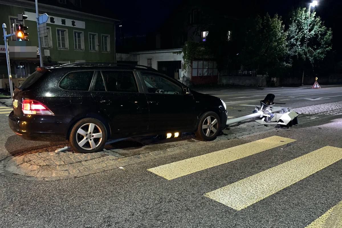 Ein schwarzer VW Kombi steht an einer Kreuzung, nachts, nachdem er eine Ampel umgefahren hat. Die Straßenlaterne liegt beschädigt am Boden.