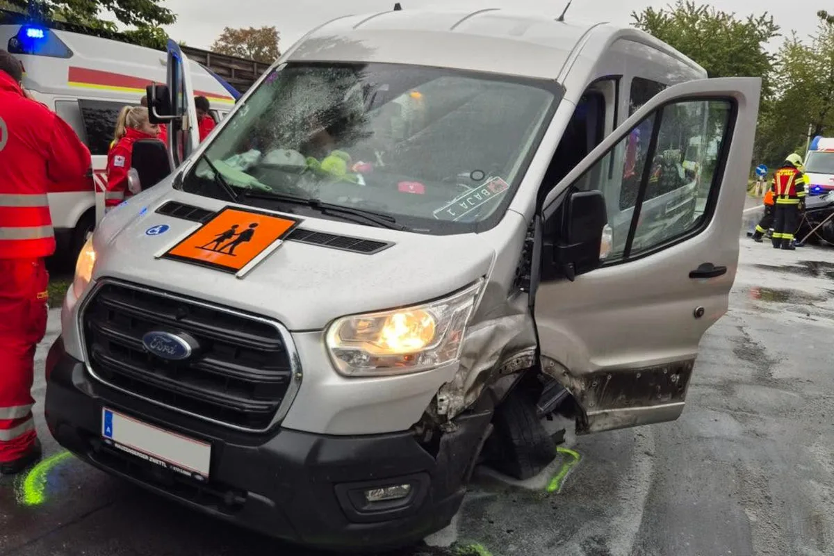 Ein silberner Van mit Frontschaden steht am Straßenrand, während Rettungskräfte daneben stehen. Die Autotür ist geöffnet.