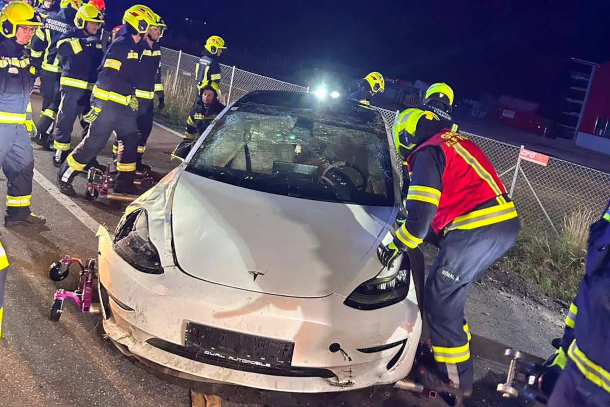 Mehrere Feuerwehrleute sind bei einem nächtlichen Rettungseinsatz vor Ort, um ein verunfalltes weißes Auto zu sichern. Das Fahrzeug weist sichtbare Schäden an der Frontpartie auf.