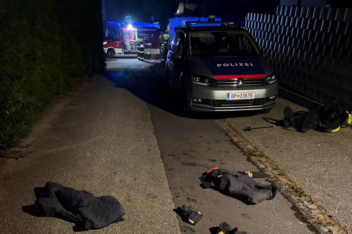 Ein Polizeiwagen und ein Feuerwehrauto stehen nachts auf einer schmalen Straße. Auf der Straße liegt verstreute Ausrüstung.