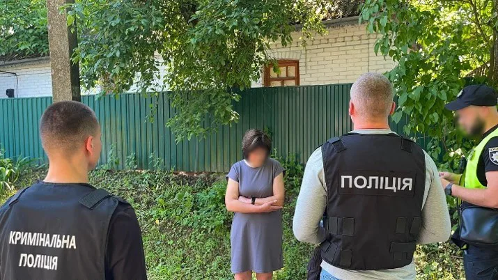 Zwei Polizisten sprechen mit einer Person in einem Garten, die von Pflanzen und einem Zaun umgeben ist.