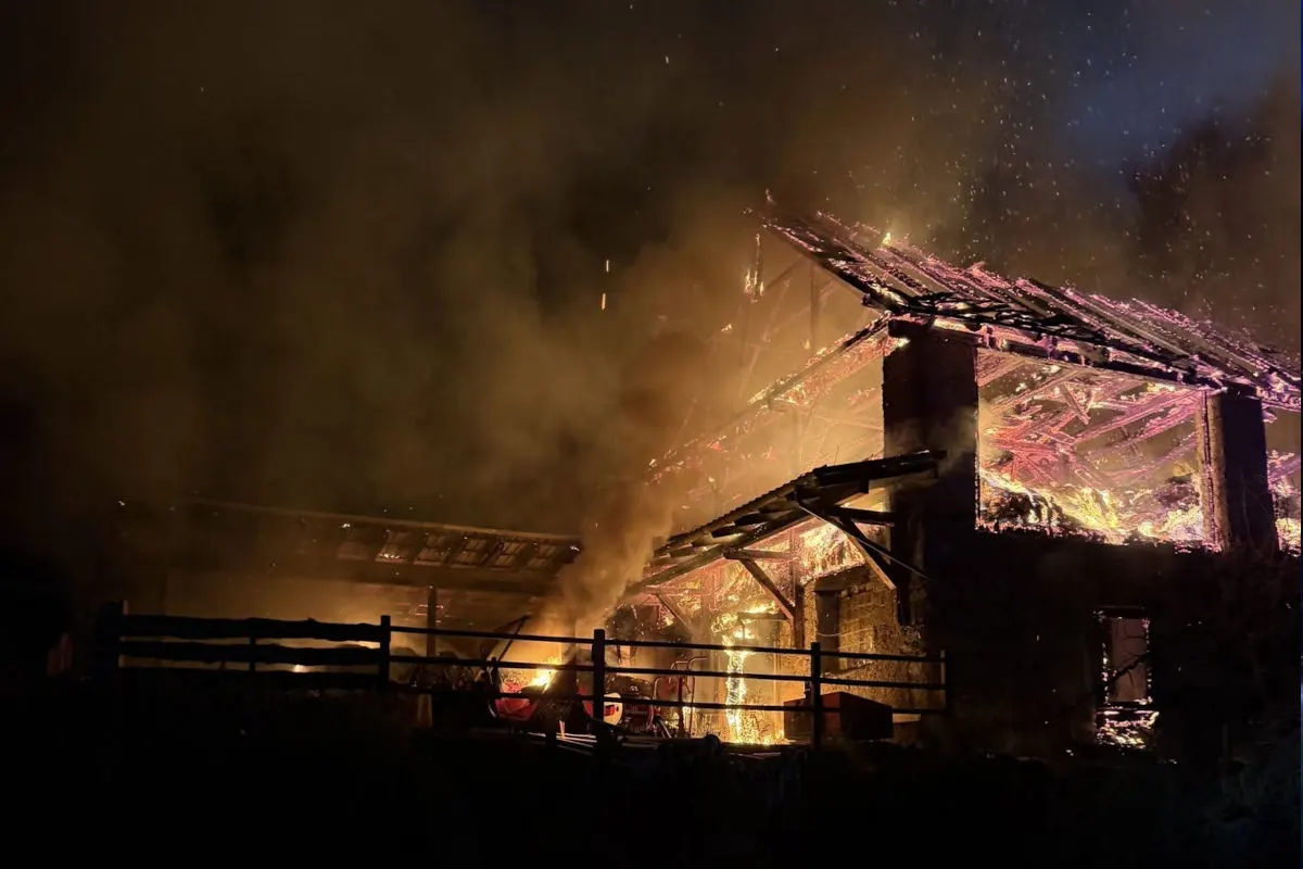 Ein Gebäude brennt in der Nacht, mit Flammen und Rauch, die aus dem Dach aufsteigen. Der Himmel ist dunkel.
