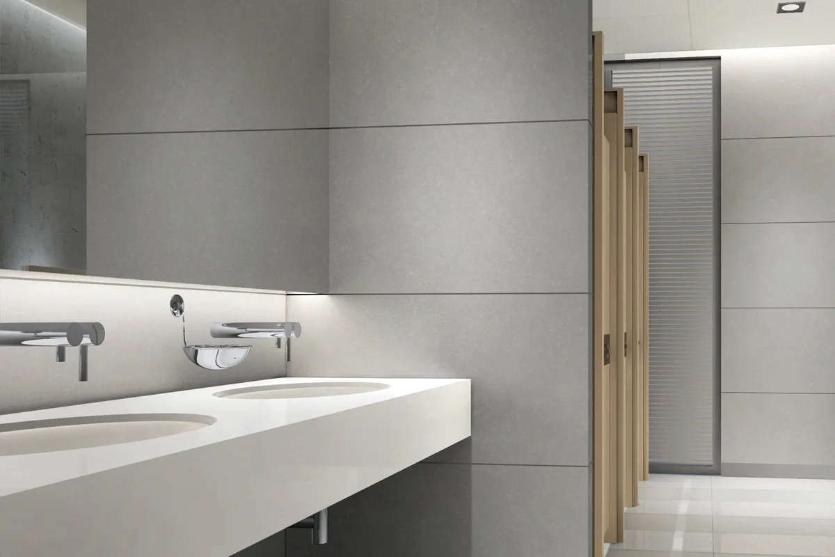 Eine moderne Toilettenanlage zeigt mehrere Waschbecken und Türen zu einzelnen Kabinen. Die Flächen sind sauber und unbenutzt.